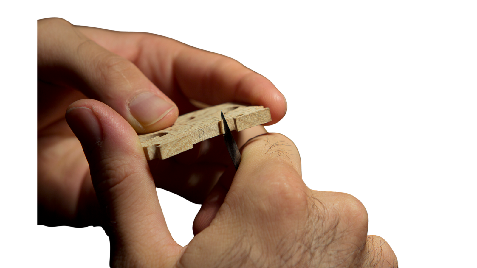 Mão do luthier ajustando o cavalete de um violino com faca